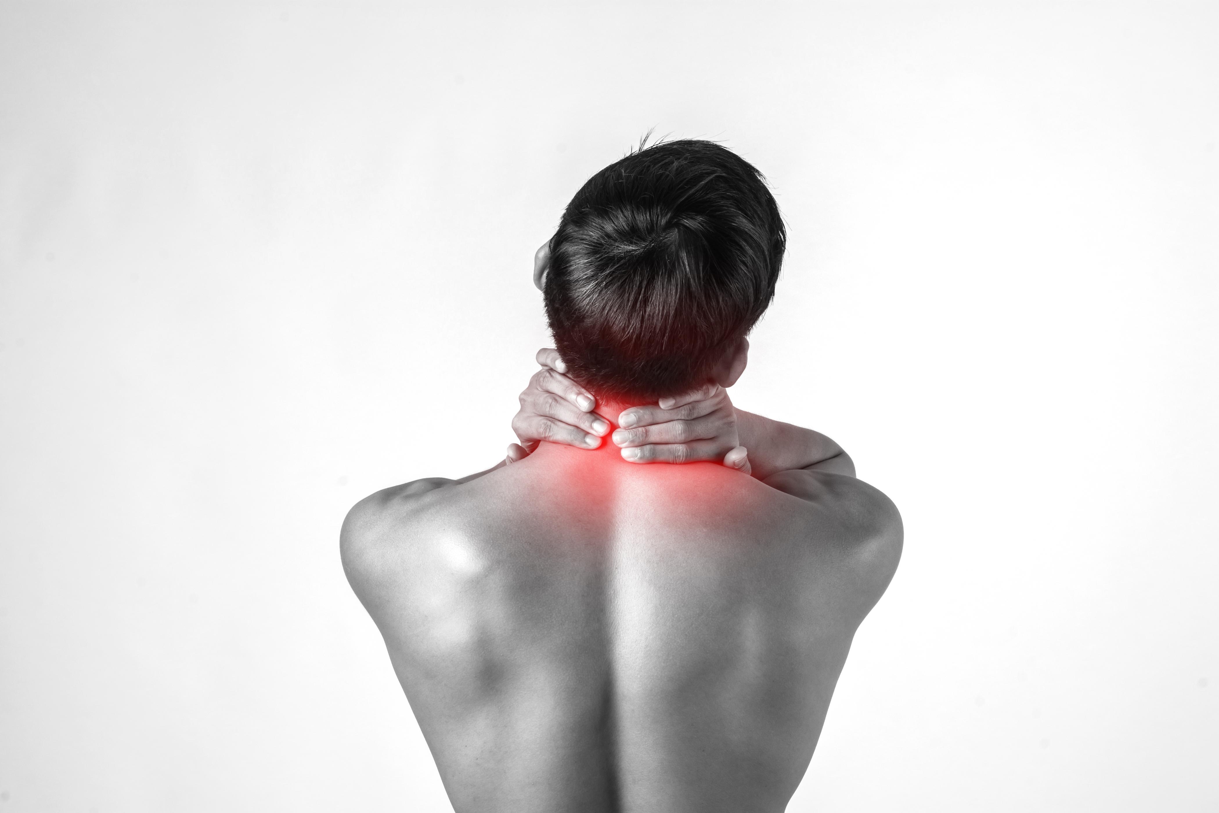 Man holding his neck in pain, highlighting cervical spine discomfort with red area indicating inflammation