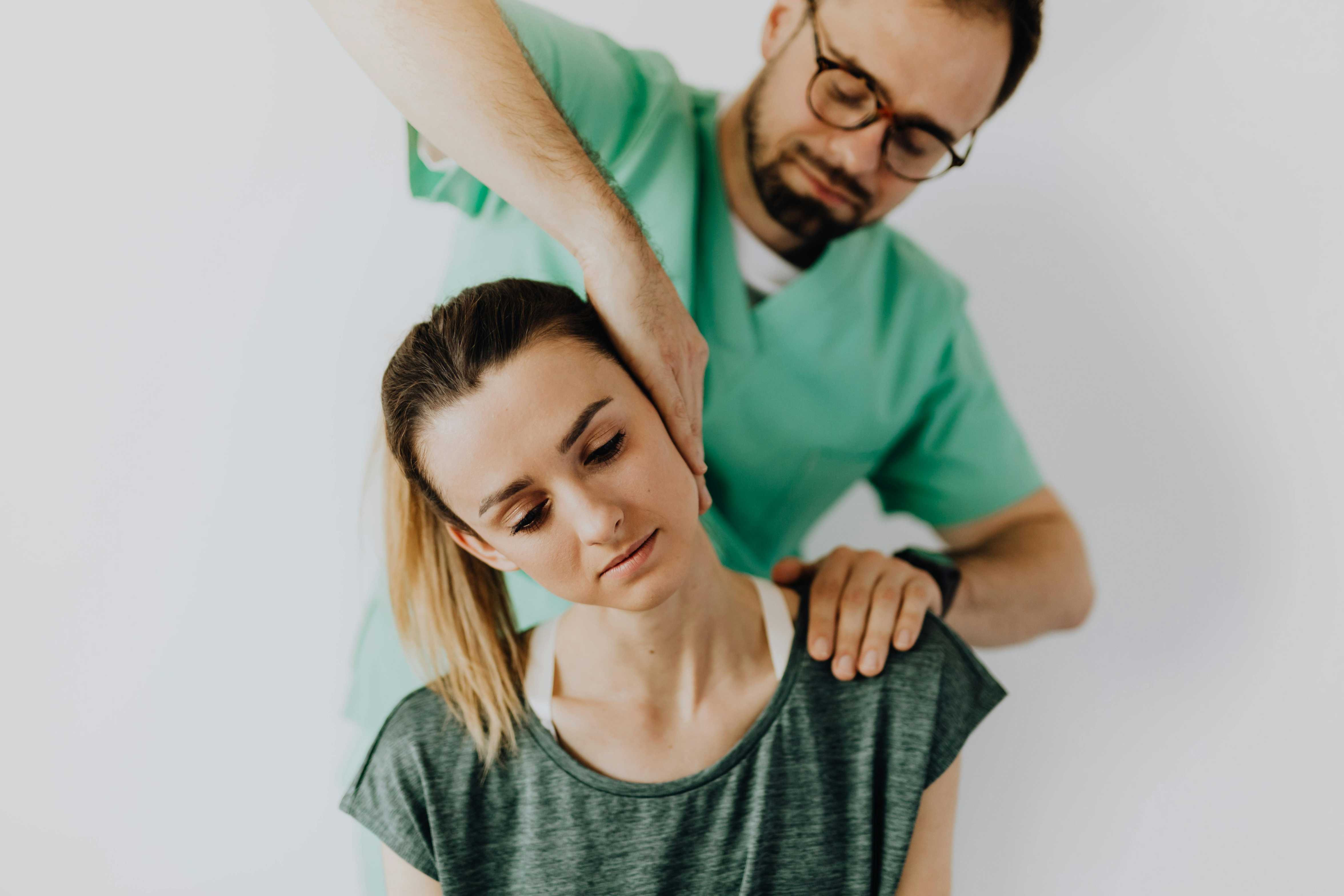 Chiropractor performing neck adjustment on a young woman for pain relief and posture correction therapy.